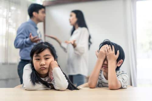 frustrated children while parents argue in background