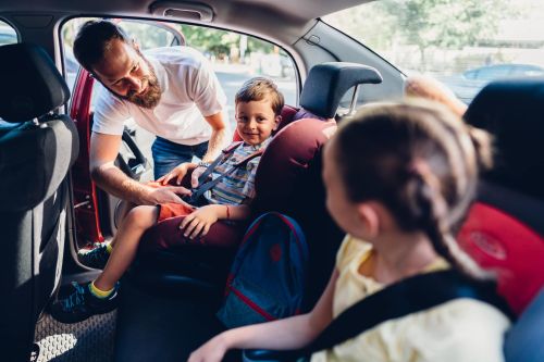 Father buckling his kids into their car seats - modifying parenting time concept