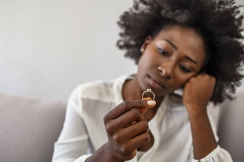 Upset african woman hold wedding ring - Common divorce mistakes concept