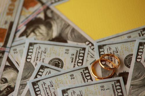 wedding rings on a pile of 100 dollar bills - how long does spousal support last concept