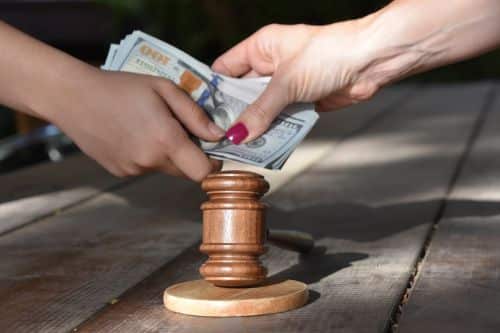 hands exchanging money over a gavel - negotiating child support concept