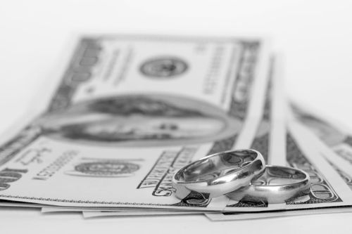 Wedding rings and money on a white background - cost of divorce concept