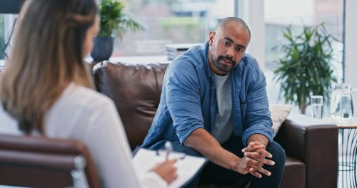 cropped shot of a therapist talking to a male patient as he sits on the couch - therapy during divorce concept