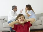 Little boy covering ears while parents fight in background - domestic violence and child custody concept