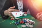 close up of someone holding cards with a large amount of chips in front of them - divorcing a gambling addict concept
